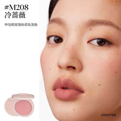 Model showcasing JOOCYEE New Loose Powder Matte Blusher in shade M208, a cool rose shade that adds a subtle pink flush to the cheeks with a velvety matte texture.